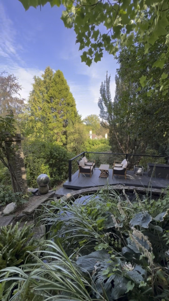 Raised entertaining deck above the pond, surrounded by mature planting